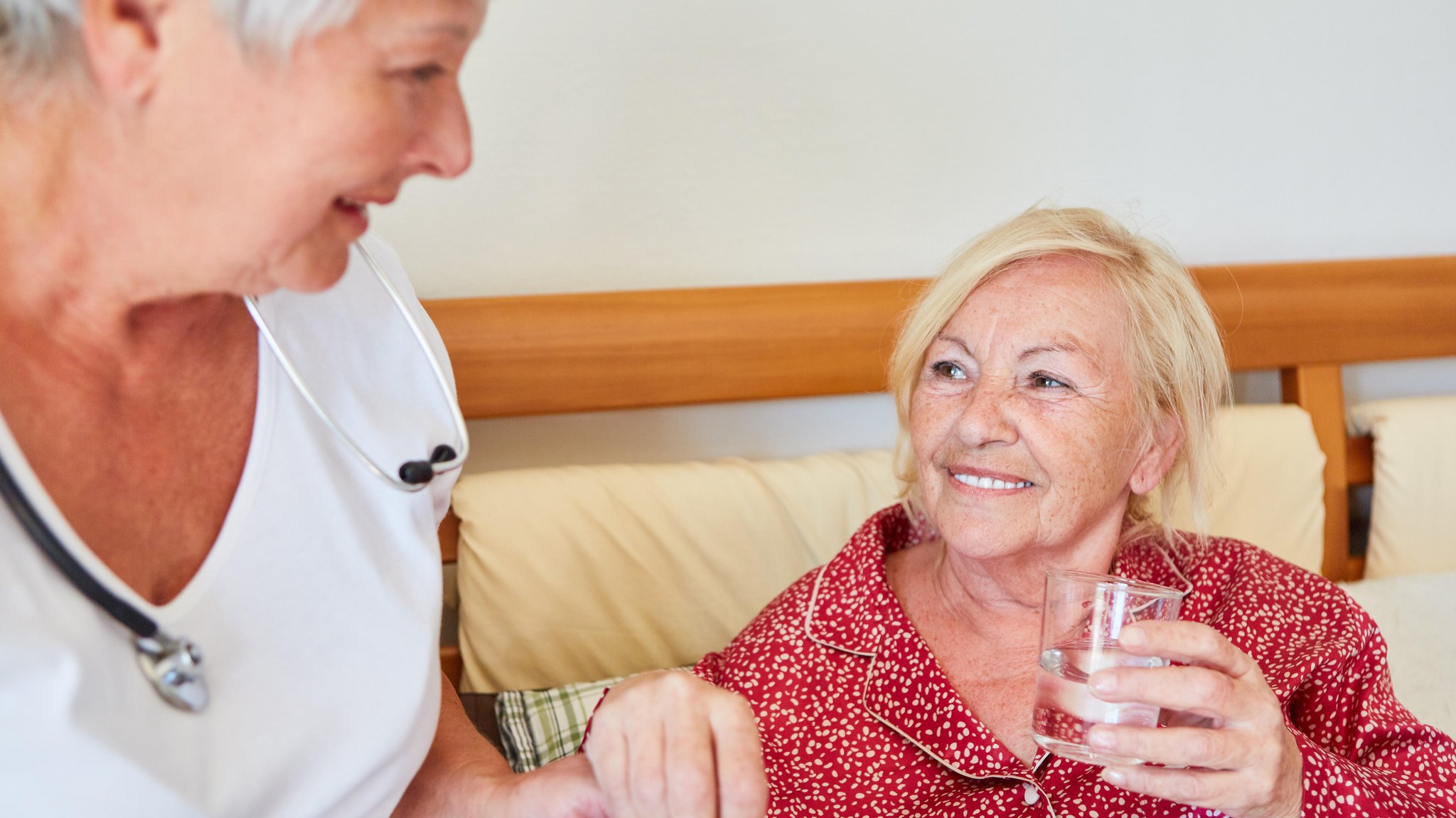 Pflegerin gibt Frau ein Wasserglas  