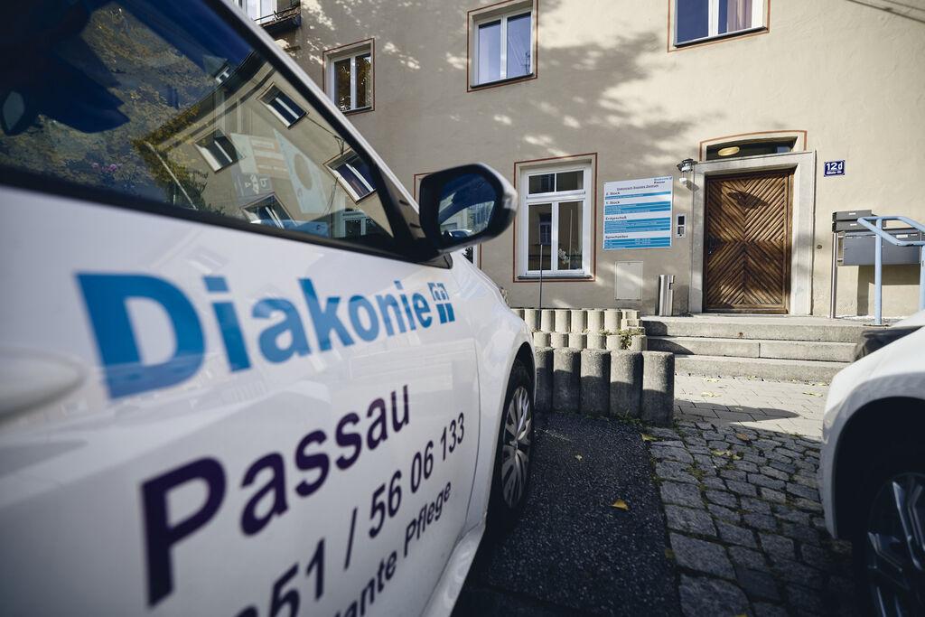 Ein Auto der Diakonie Passau steht vor einem Gebäude