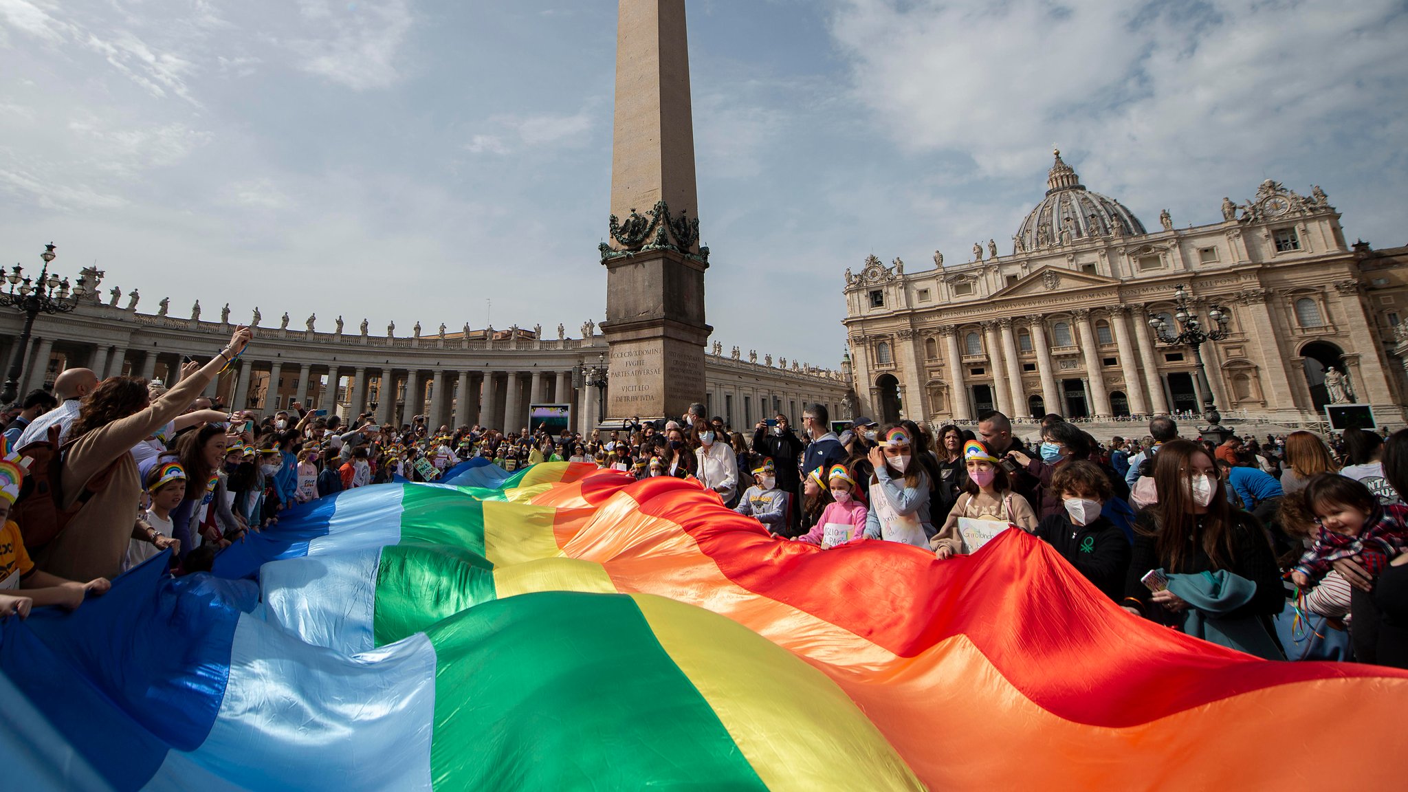 Kinder halten eine Regenbogenfahne, während Papst Franziskus während seines Angelus-Gebets aus dem Fenster des Apostolischen Palastes, der über den Petersplatz blickt, zu der Menge spricht.