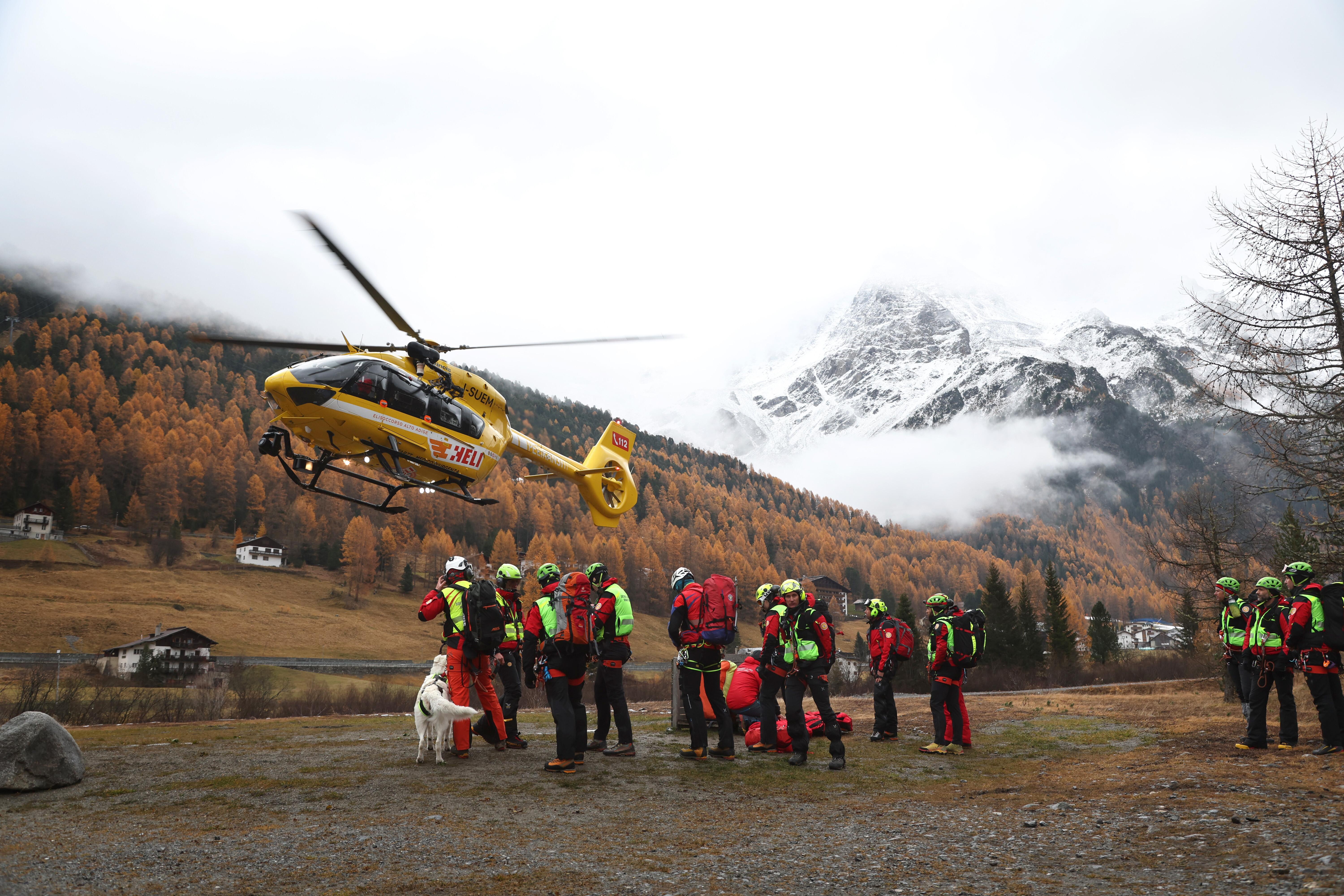 Ein Hubschrauber der Bergrettung landet vor Bergrettern.
