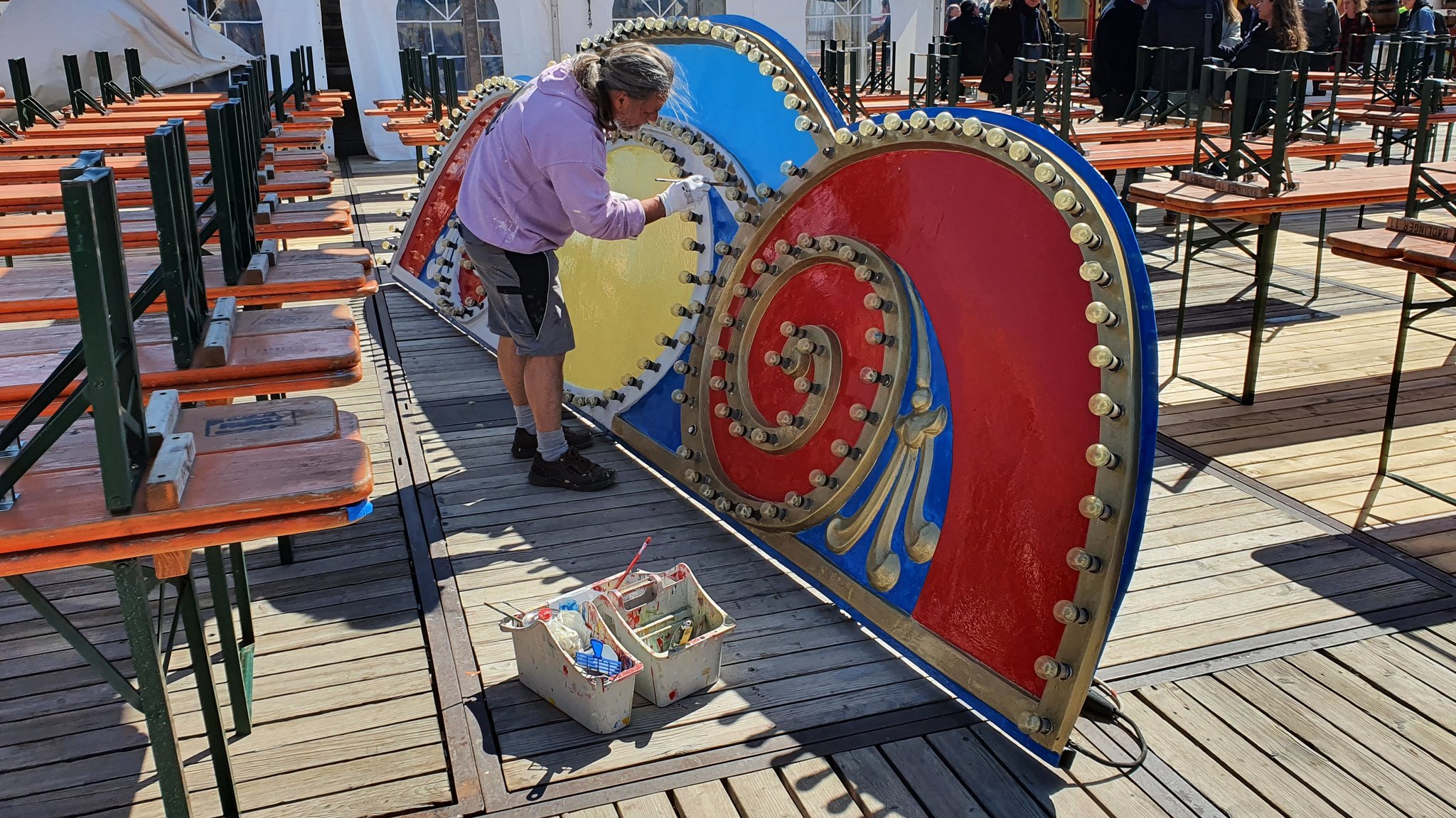 Ein Schausteller bemalt ein Schild fürs Frühlingsfest in München.