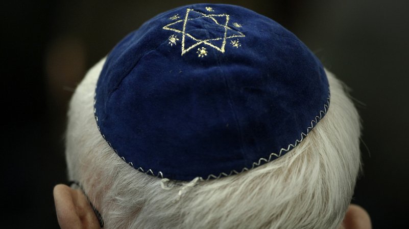 Ein Mann trägt in einer Synagoge eine Kippa mit einem aufgenähtem Davidstern.