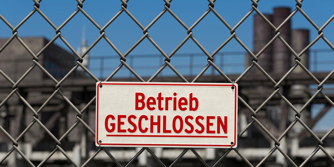 Schild: Betrieb geschlossen an einem Zaun vor einem Werksgelände.