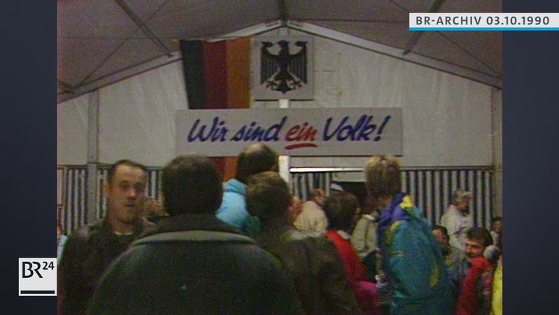 Menschen in einem Zelt, Banner mit der Aufschrift "Wir sind ein Volk!"