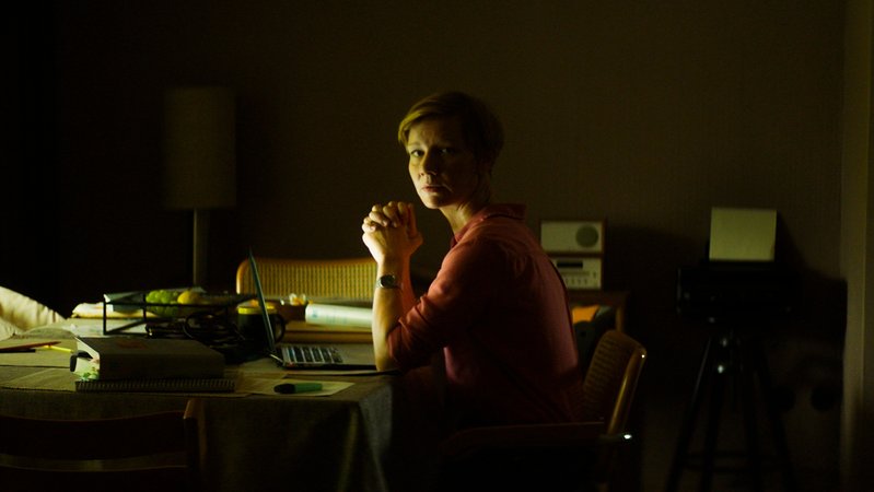 In einem schwach beleuchteten Zimmer sitzt eine Frau mit Laptop am Schreibtisch: Sandra Hüller als besorgte Ehefrau in "Exil" (Filmszene).
