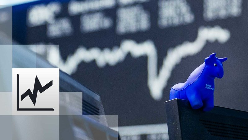 ein blauer Stier aus Gummi sitzt auf der oberen Kante eines Bildschirmes, im Hintergrund die Kurstafel der Börse