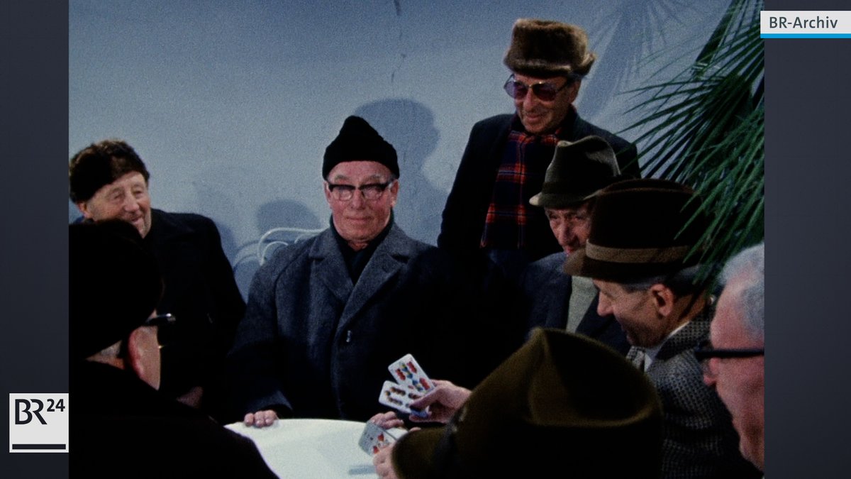 Rentner in Wintermänteln mit Pelzmützen und Hüten beim Kartenspiel in der Wärmestube 