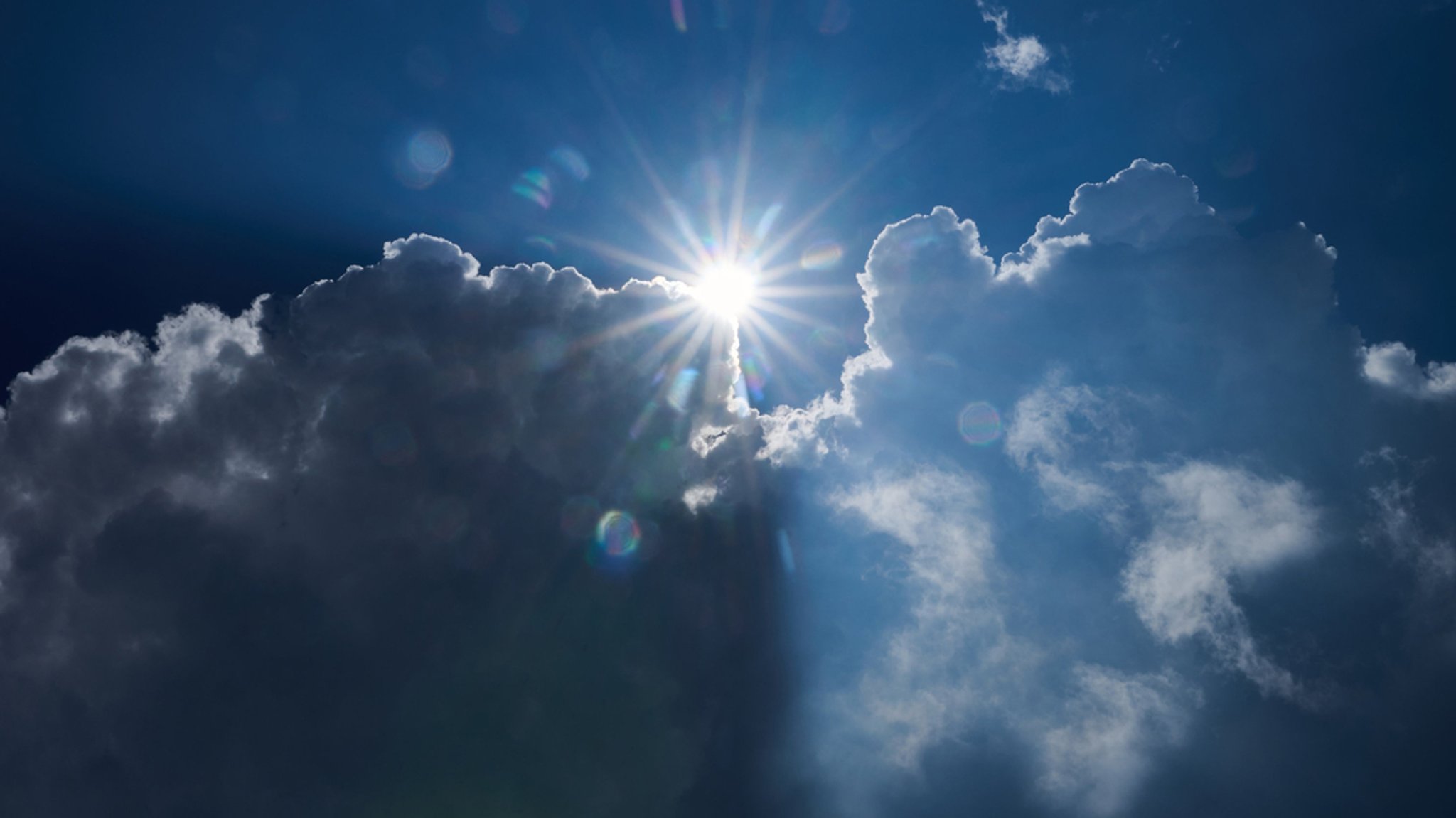 Die Sonne scheint am Rand von dunklen Wolken.