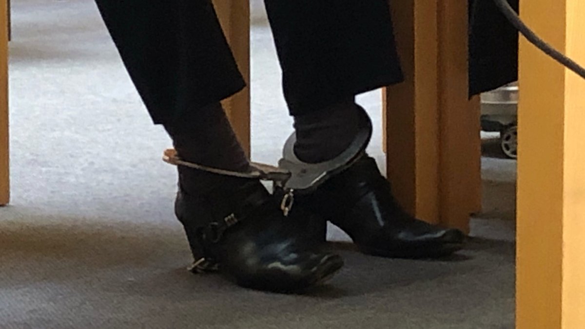 Eine Frau mit Fußfesseln auf der Anklagebank des Weidener Landgerichts