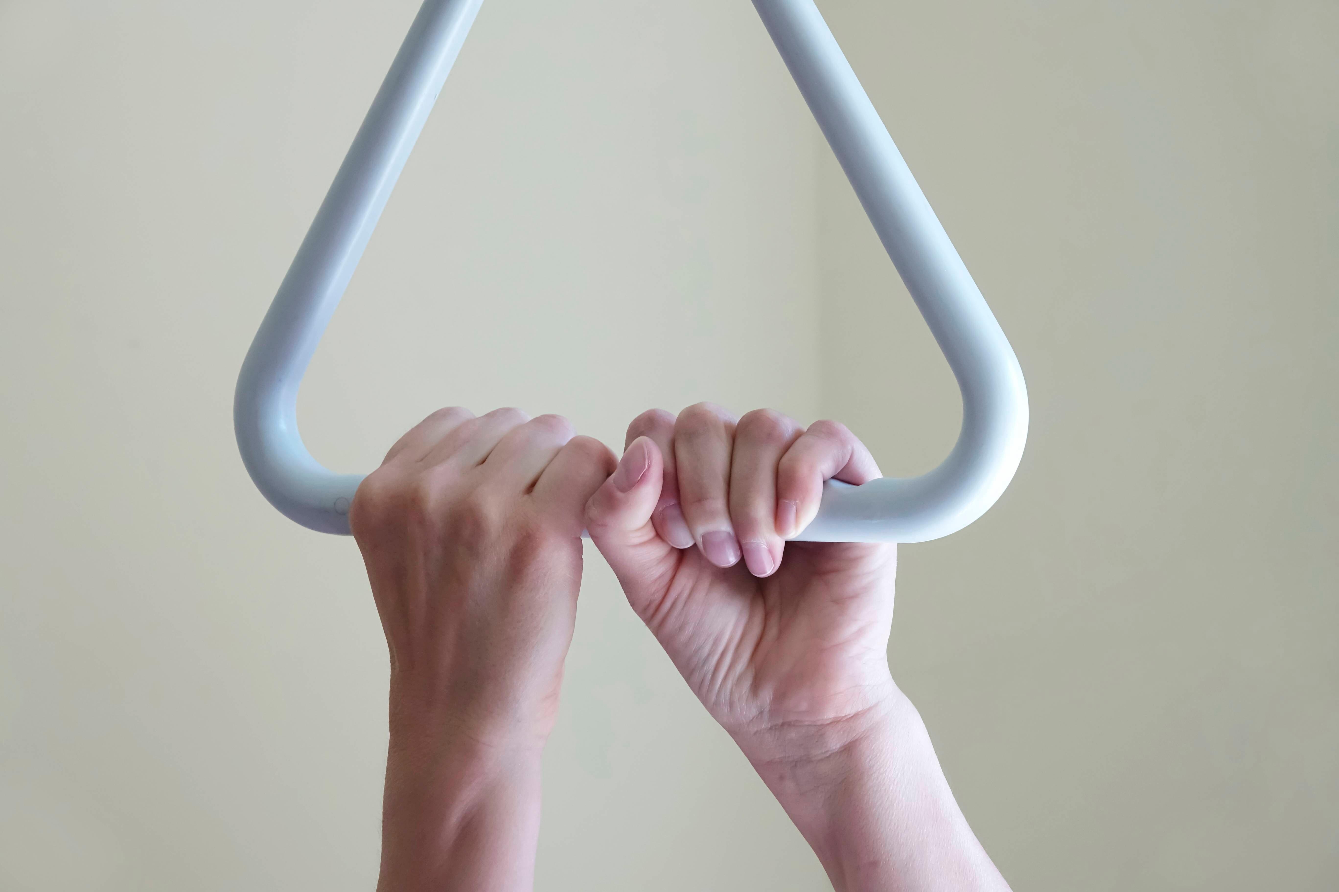 Zwei Hände halten sich am Griff eines Krankenhausbettes fest (Symbolbild)