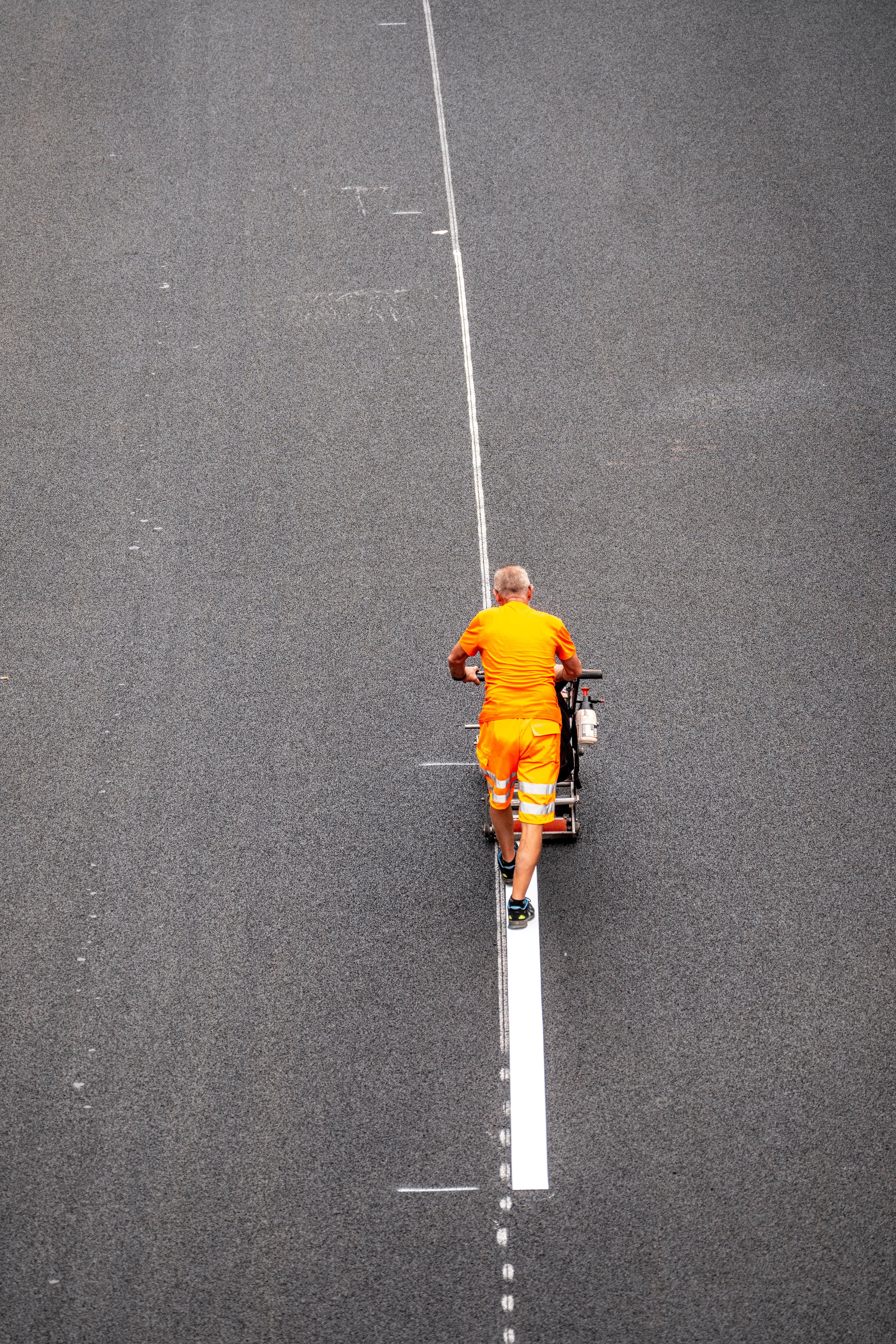 (Symbolbild) Auf einer Autobahn markiert ein älterer Mitarbeiter die Spur.