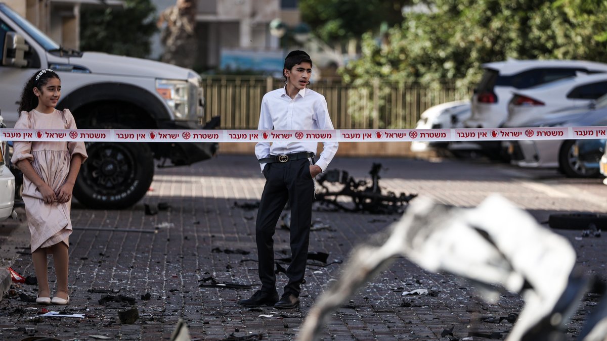 Anwohner im israelischen Ashkelon betrachten die Trümmer zerstörter Fahrzeuge nach einem Raketenangriff aus Gaza.