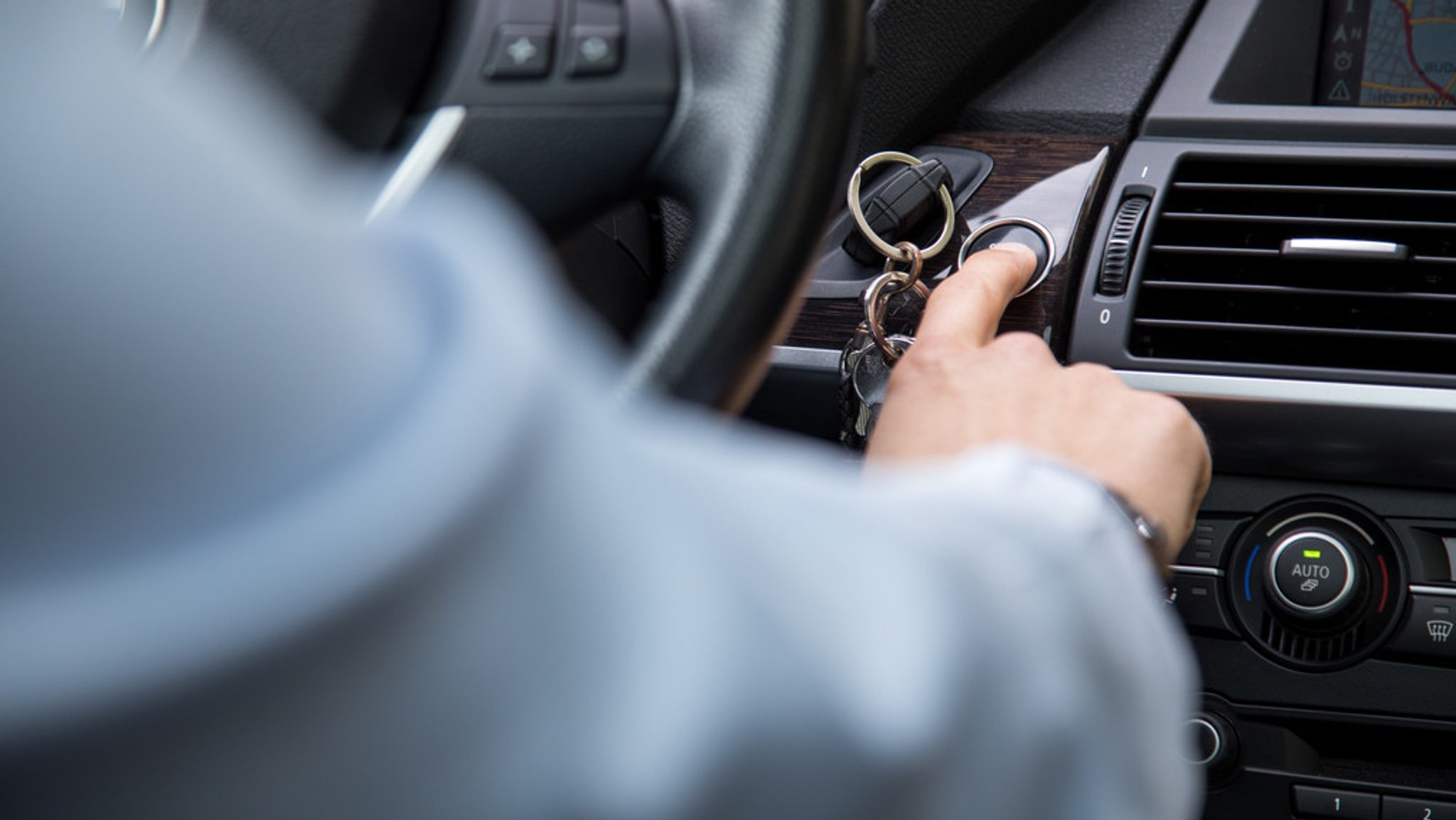 Eine Person startet im Auto den Motor (Symbolbild)