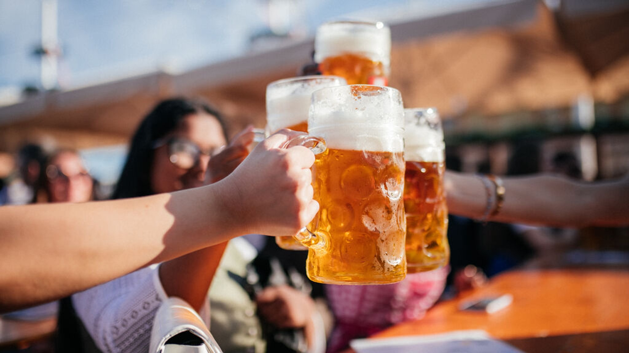 Vier Frauen stoßen in einem Biergarten auf der Wiesn zusammen mit einer Maß Bier an (Symbolbild).