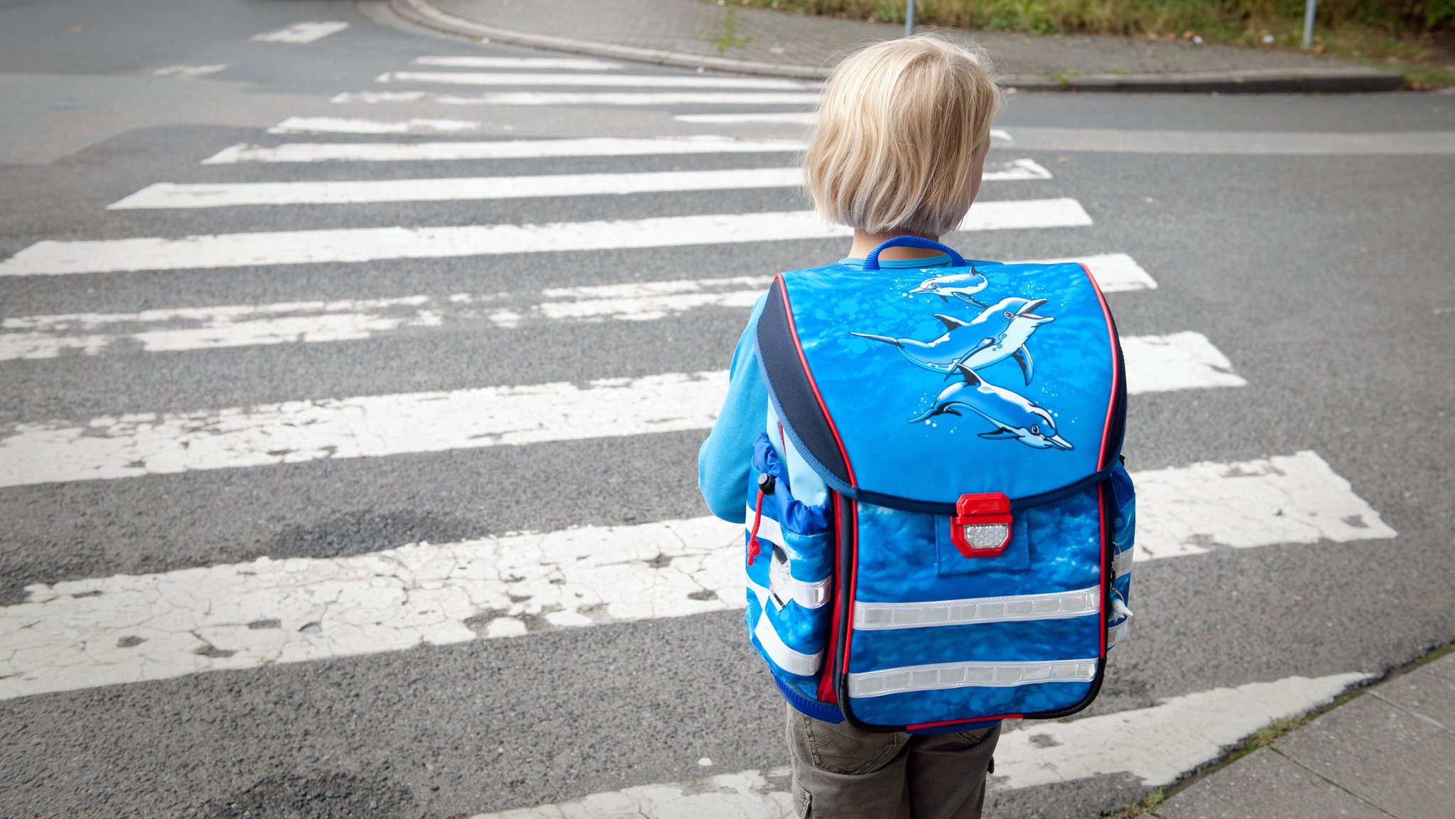 Ein Mädchen hält auf dem Schulweg an einem Zebrastreifen. (Symbolbild)