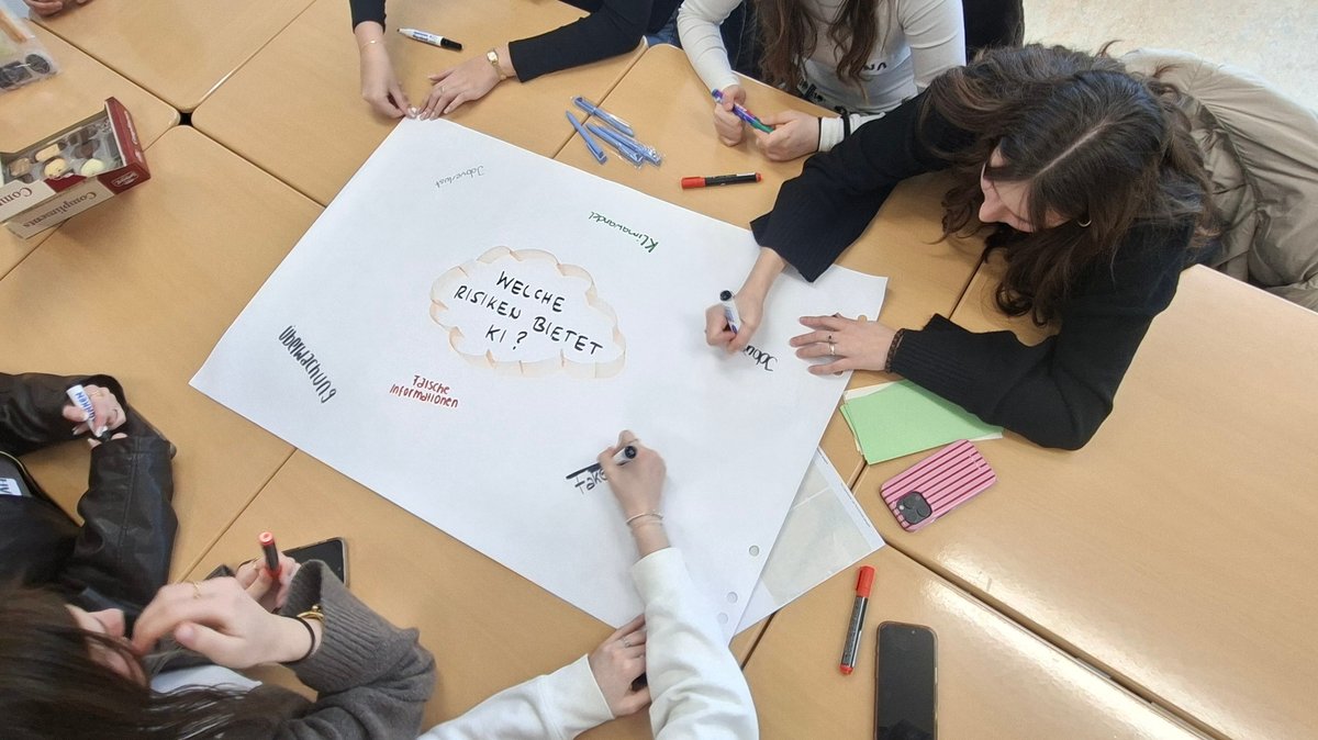 Schülerinnen schreiben auf ein Plakat, welche Risiken sie in der Künstlichen Intelligenz sehen.