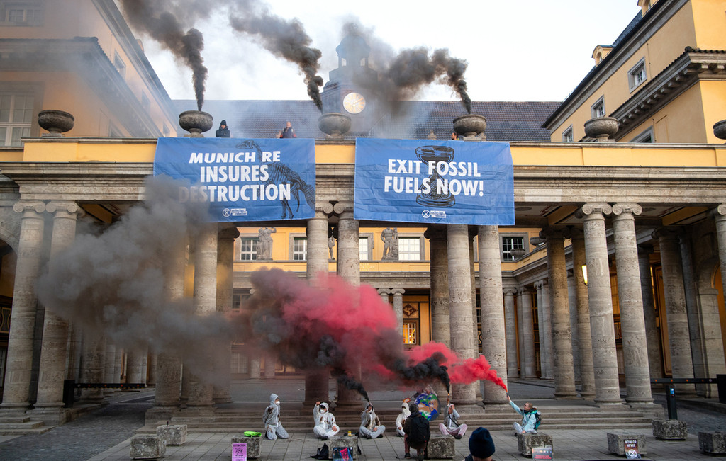 Aktivisten der Gruppe Extinction Rebellion demonstrieren am Firmensitz von Munich Re und haben Plakate mit der Aufschrift «Munich Re destruction» und «Exit Fossil Fuels now» am Gebäude angebracht. 