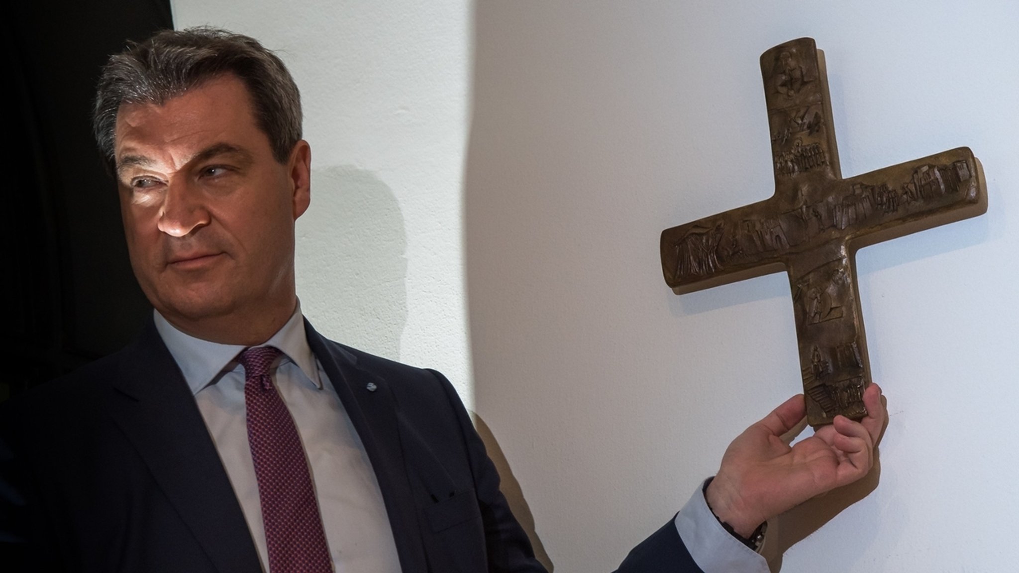 Ministerpräsident Söder (CSU) hängt ein Kreuz im Eingangsbereich der bayerischen Staatskanzlei auf