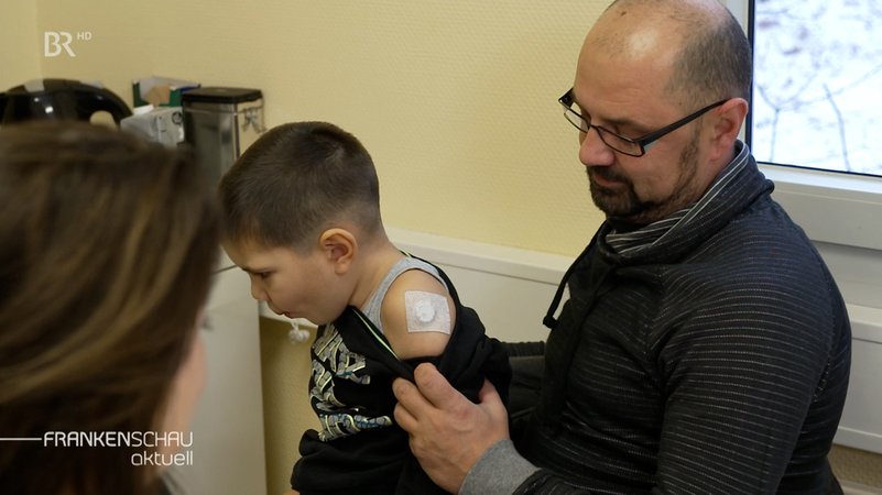 Junge mit Diabetes-Sensor am Arm.