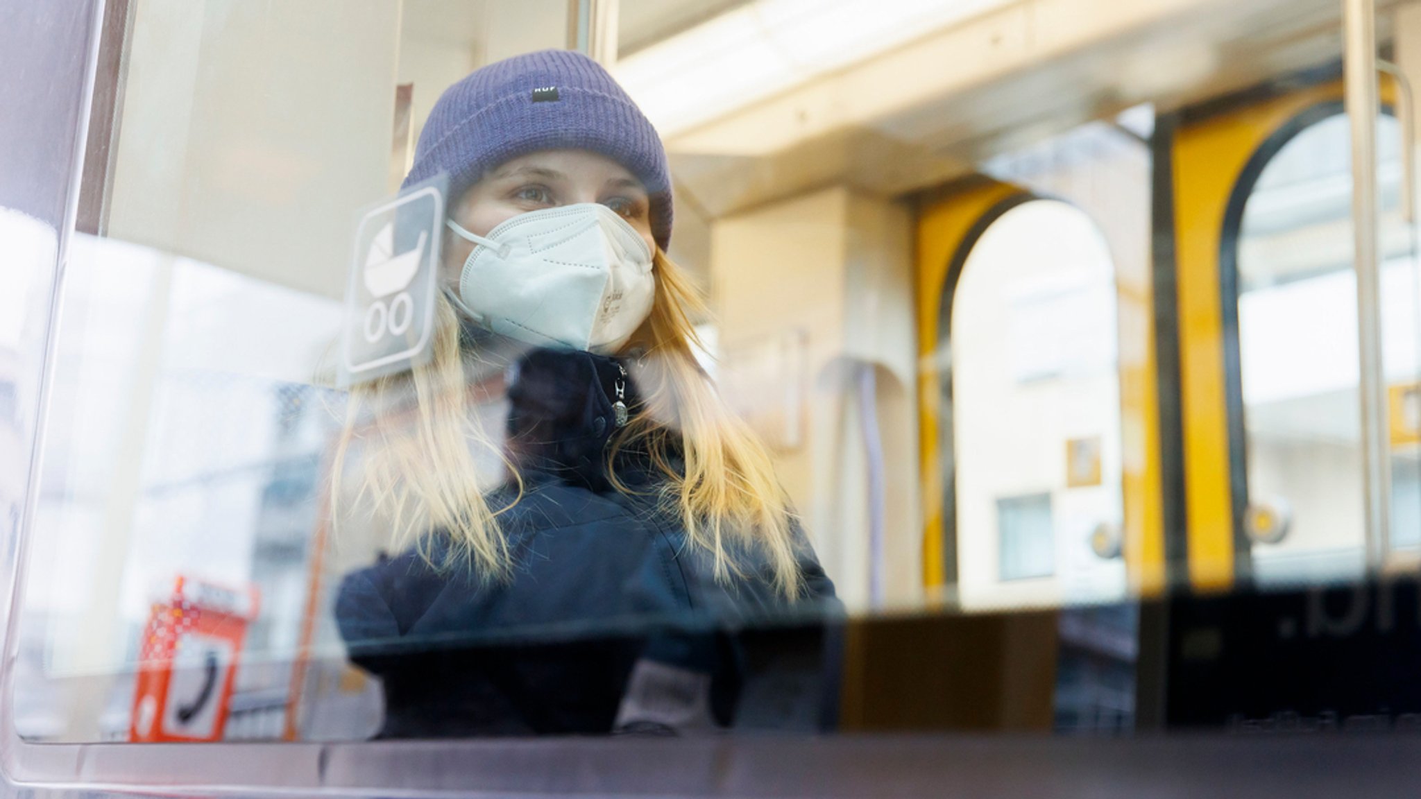 Eine Frau mit Maske sitzt in einer Straßenbahn