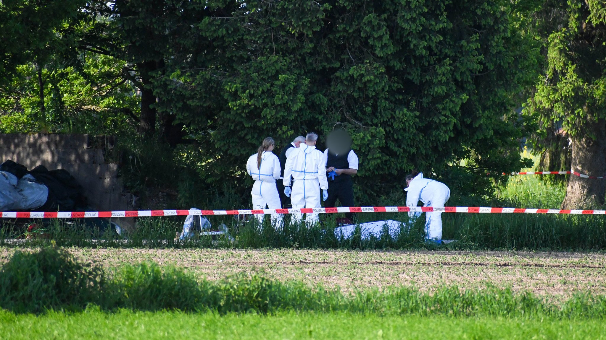 Mitarbeiter der Spurensicherung und Bestatter stehen am Fundort einer Frauenleiche bei Sauerlach. 