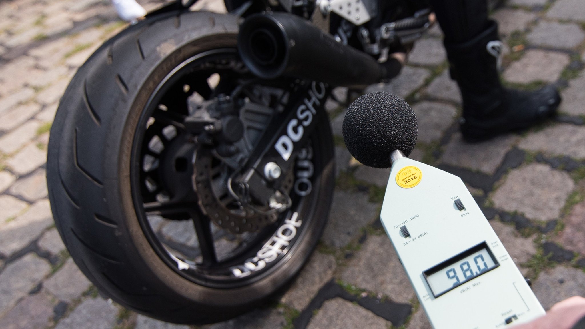 Ein Mitarbeiter des TÜV kontrolliert die Lautstärke eines Motorrad-Auspuffs.