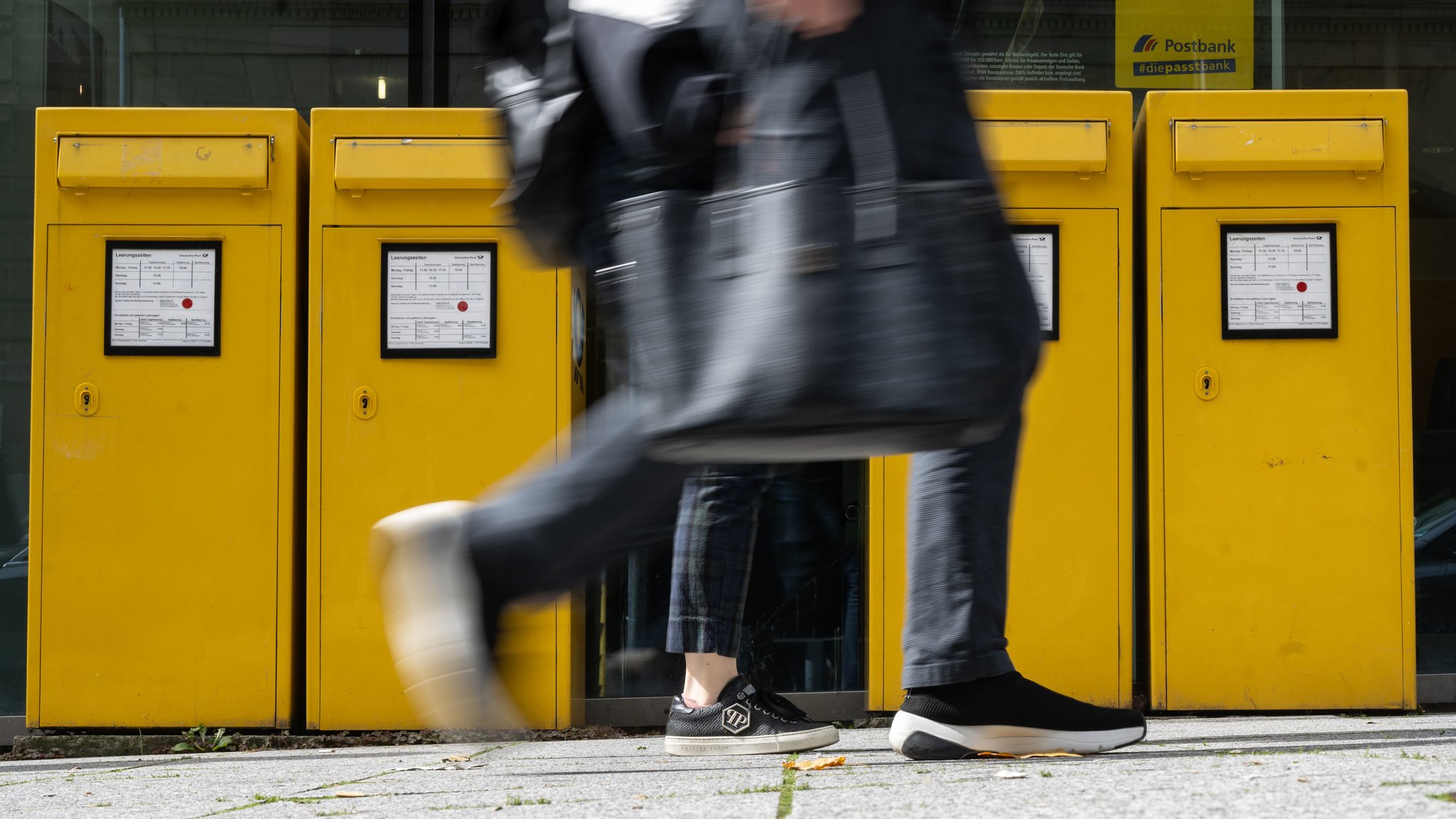 Zwei Menschen gehen an Briefkästen vorbei (Symbolbild).