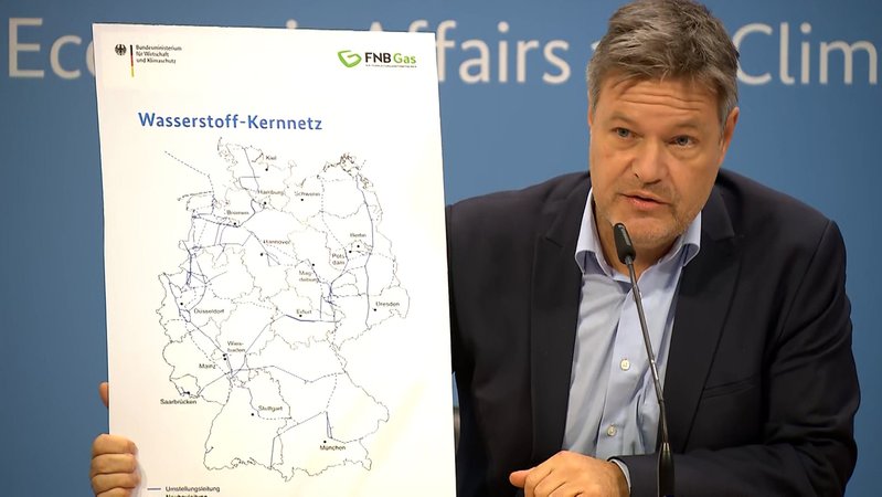 Wirtschaftsminister Robert Habeck (Grüne) hält eine Karte zum Wasserstoff-Kernnetz in der Hand.