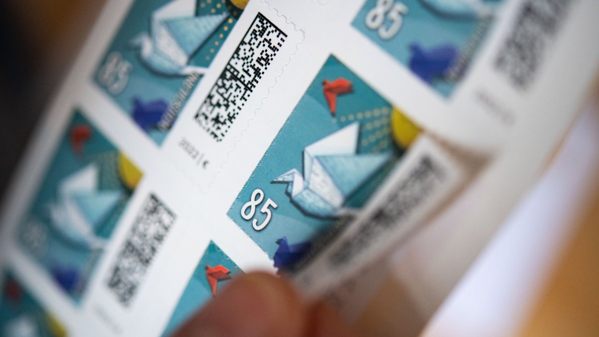 Eine Frau löst eine 85 Cent Briefmarke von einem Bogen. 