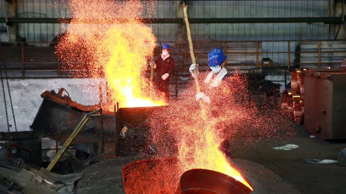 Arbeiter mit Schutzbrille und Mundschutz schmelzen Kupferrohre in einer Metall-Verarbeitungsstätte der ostchinesischen Provinz Zhejiang.