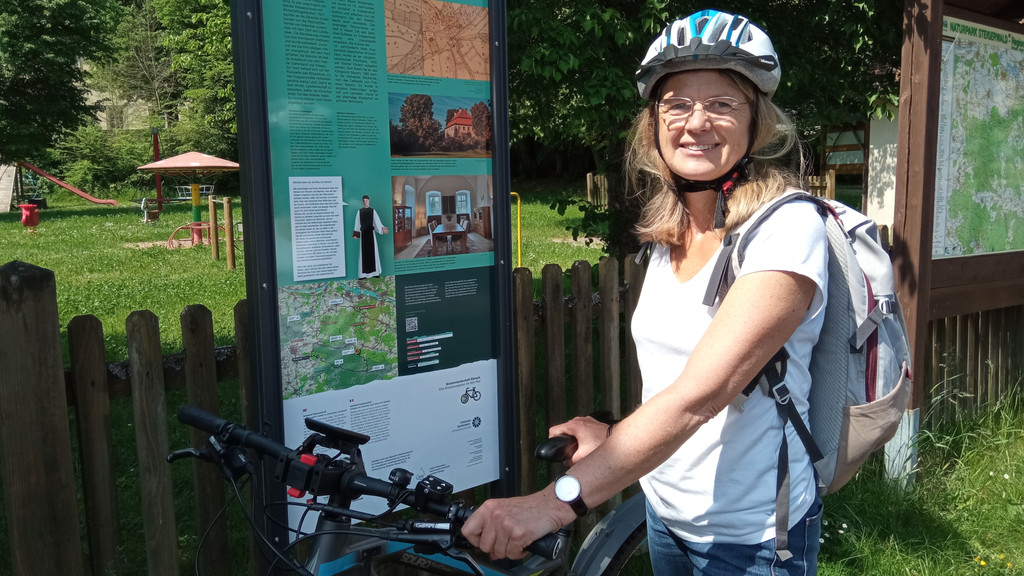 Die Radrunden-Projektleiterin Ulla Schmidt steht mit ihrem Fahrrad vor einer Informationsstele in Koppenwind.