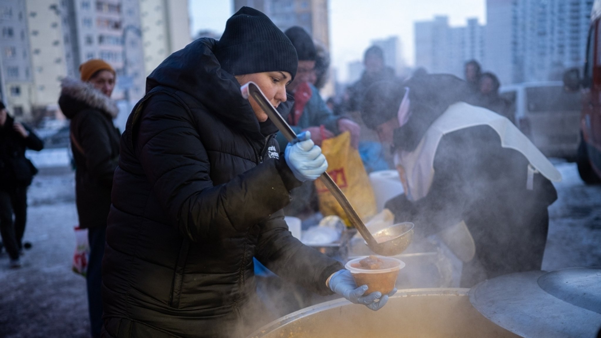 21.01.2026, Ukraine, Kiew: Eine Freiwillige serviert den Einwohnern von Kiew während eines Stromausfalls, der durch die regelmäßigen russischen Luftangriffe auf das Energiesystem des Landes verursacht wurde, kostenlos warmes Essen.