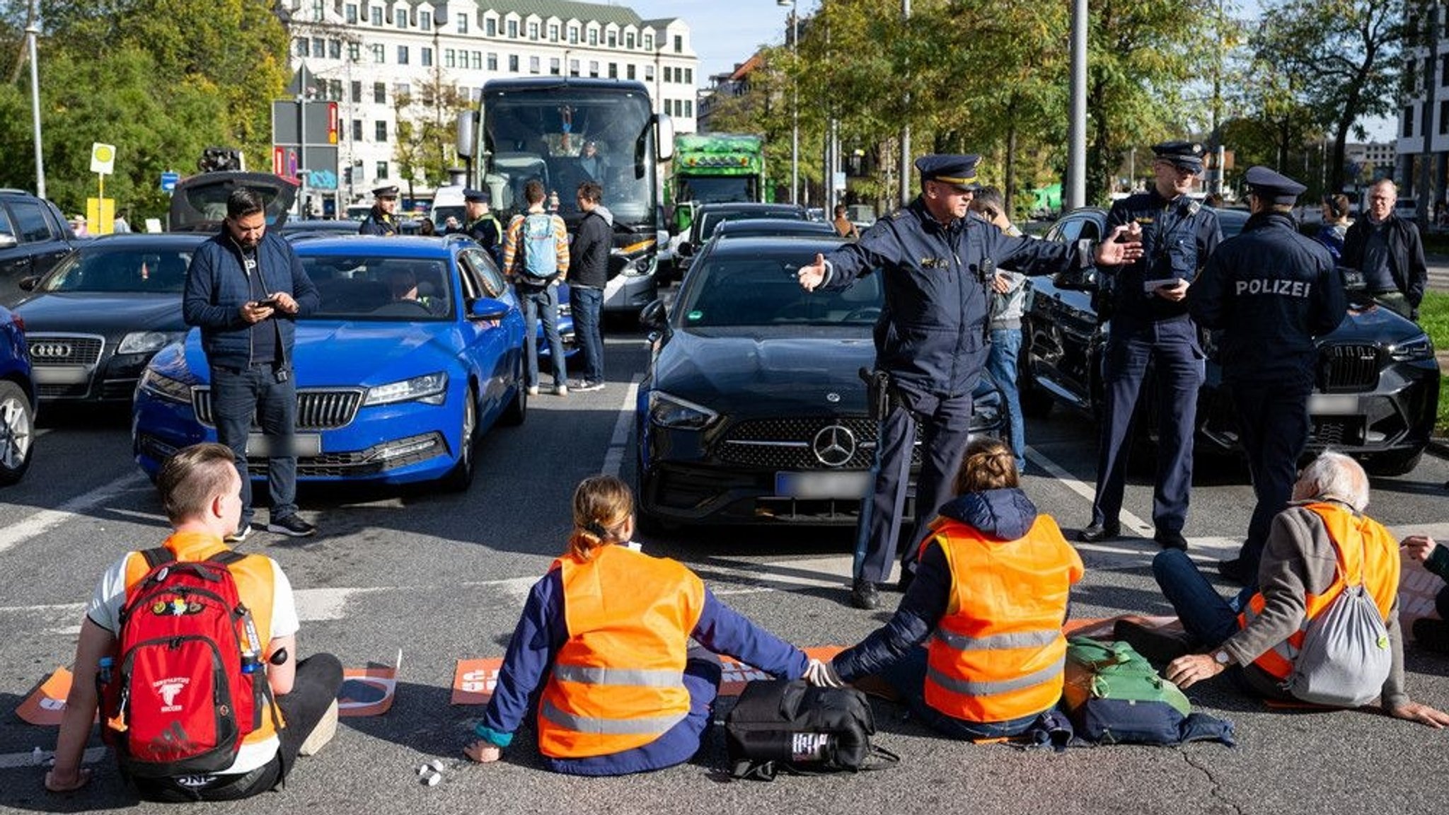 3.11: Klimaaktivisten haben sich am Karlsplatz in der Münchner Innenstadt auf die Fahrbahn geklebt und blockieren die Straße.