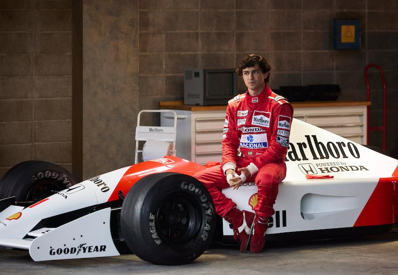 Gabriel Leone alias Ayrton Senna in einem roten Rennfahreranzug auf einem Honda-Rennwagen sitzend, Szene aus der Serie "Senna"