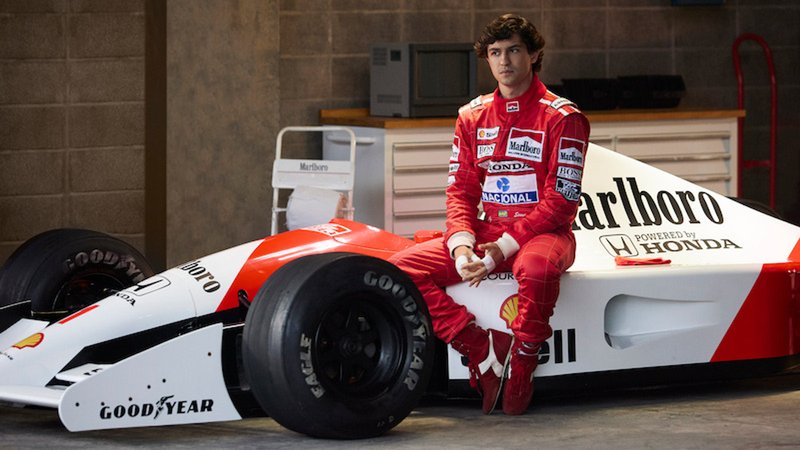 Gabriel Leone alias Ayrton Senna in einem roten Rennfahreranzug auf einem Honda-Rennwagen sitzend, Szene aus der Serie "Senna" | Bild: Alan Roskyn/ Netflix Gabriel Leone alias Ayrton Senna in einem roten Rennfahreranzug auf einem Honda-Rennwagen sitzend, Szene aus der Serie "Senna"