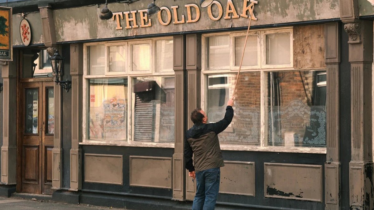 Ein Mann repariert den Schriftzug "The Old Oak" übe reinem Pub. 