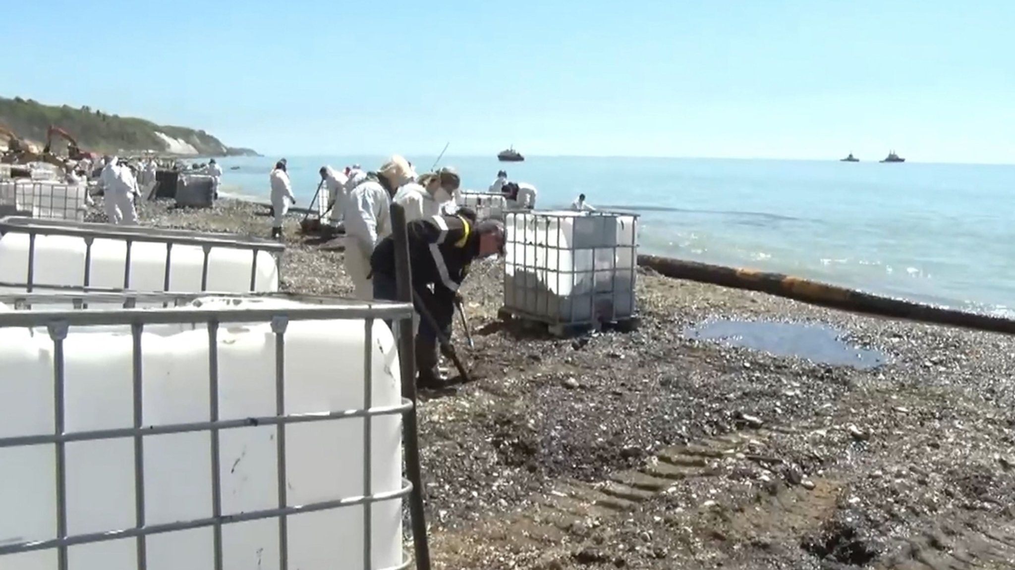 29.04.2026, Russland, Tuapse: In diesem Bild aus einem Video, das auf dem Telegram-Kanal des Gouverneurs der Region Krasnodar, Weniamin Kondratjew, veröffentlicht wurde, sammeln Menschen nach einem Drohnenangriff auf die Ölraffinerie und das Ölterminal in Tuapse Öl am Strand ein.