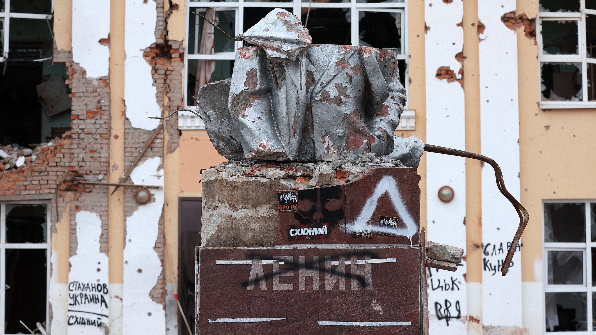 Zertrümmerte Hausfassade im Hintergrund, davor zerbeultes Metall