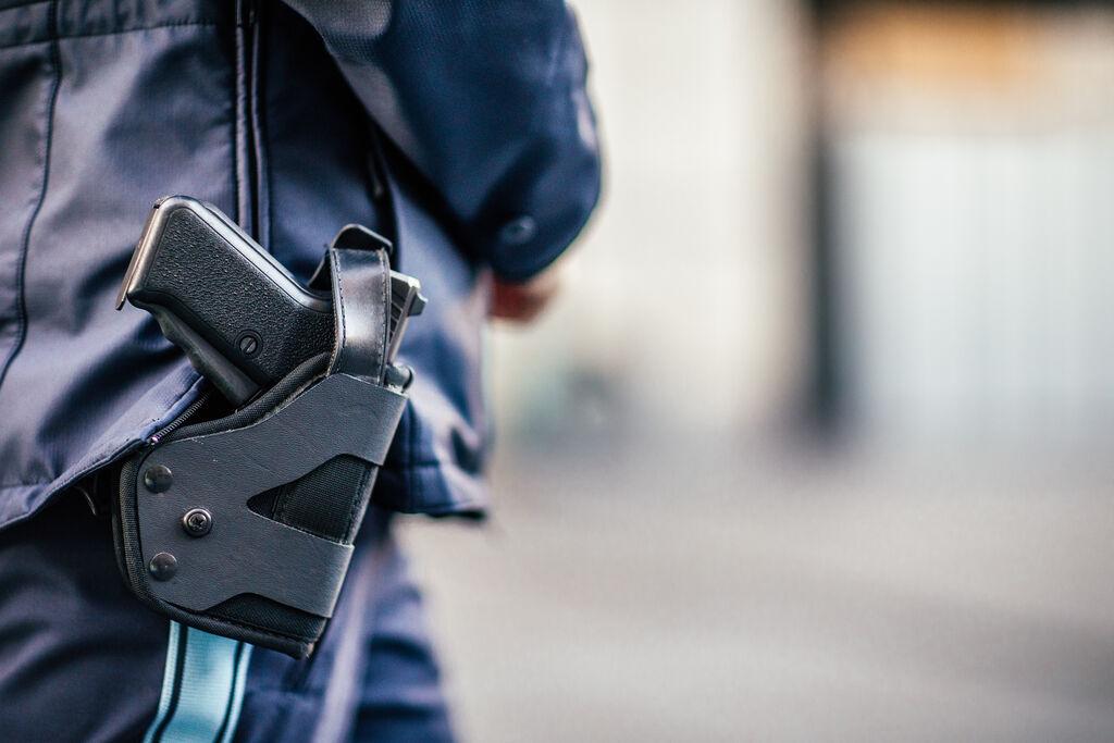 Am Einsatzgürtel einer Polizistin hängt ein Holster mit eine Waffe.