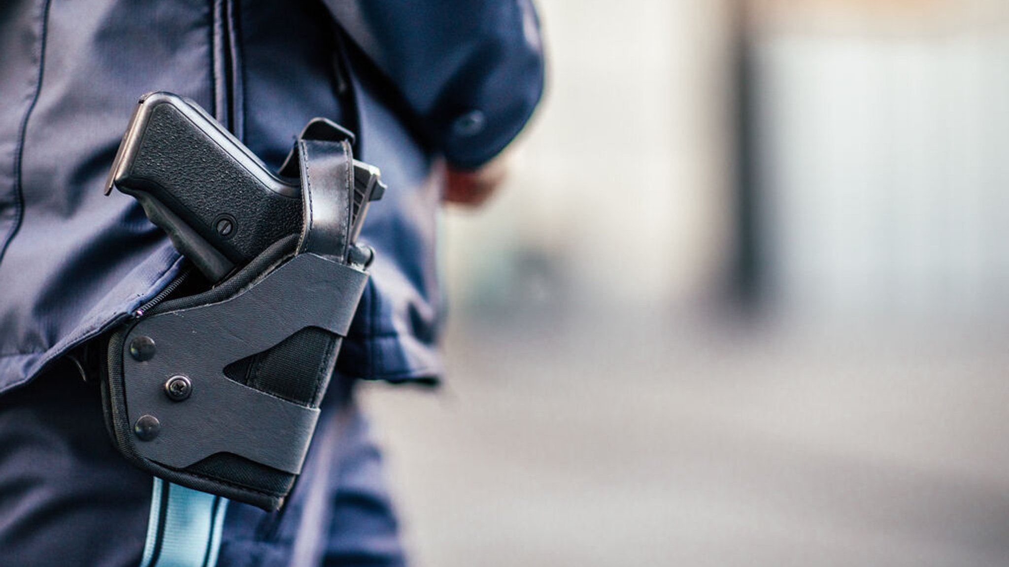 Am Einsatzgürtel einer Polizistin hängt ein Holster mit eine Waffe.