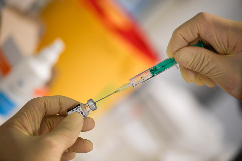 Ein Arzt zieht eine Spritze mit Covid-19 Impfstoff auf