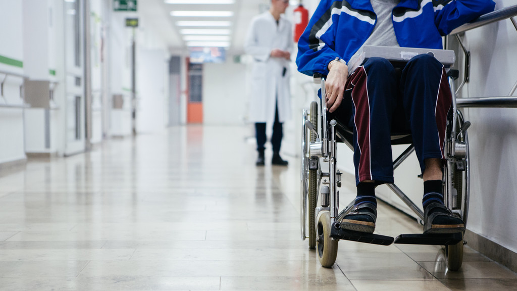 Ein Rollstuhlfahrer wartet im Gang eines Krankenhauses (Symbolbild).