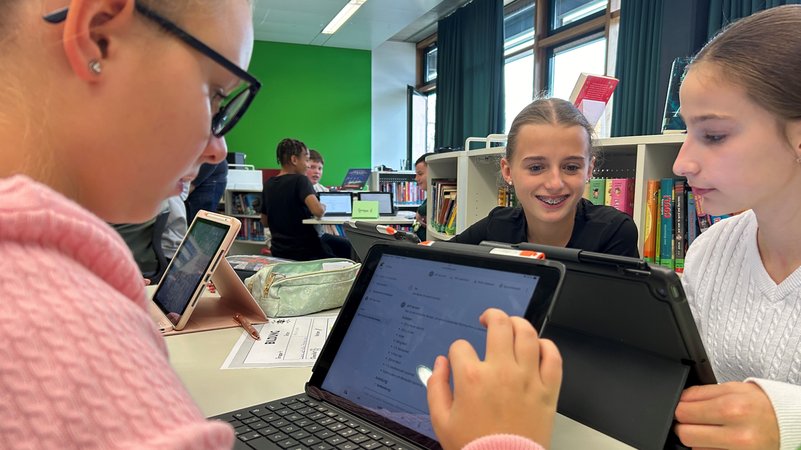 Drei Schülerinnen sitzen am Tisch und schauen auf ihr Tablet. | Bild: Theresa Momsen / BR Drei Schülerinnen sitzen am Tisch und schauen auf ihr Tablet.