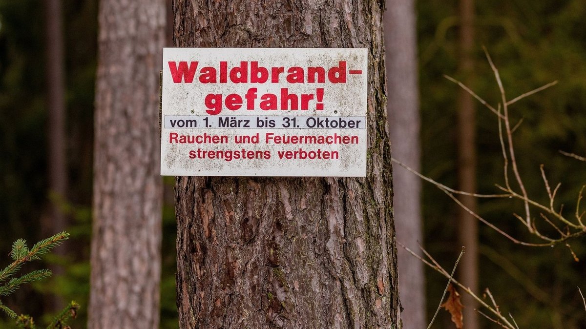 Ein Schild an einem Baum warnt vor Waldbränden und verbietet offenes Feuer und Rauchen im Wald (Symbolbild).