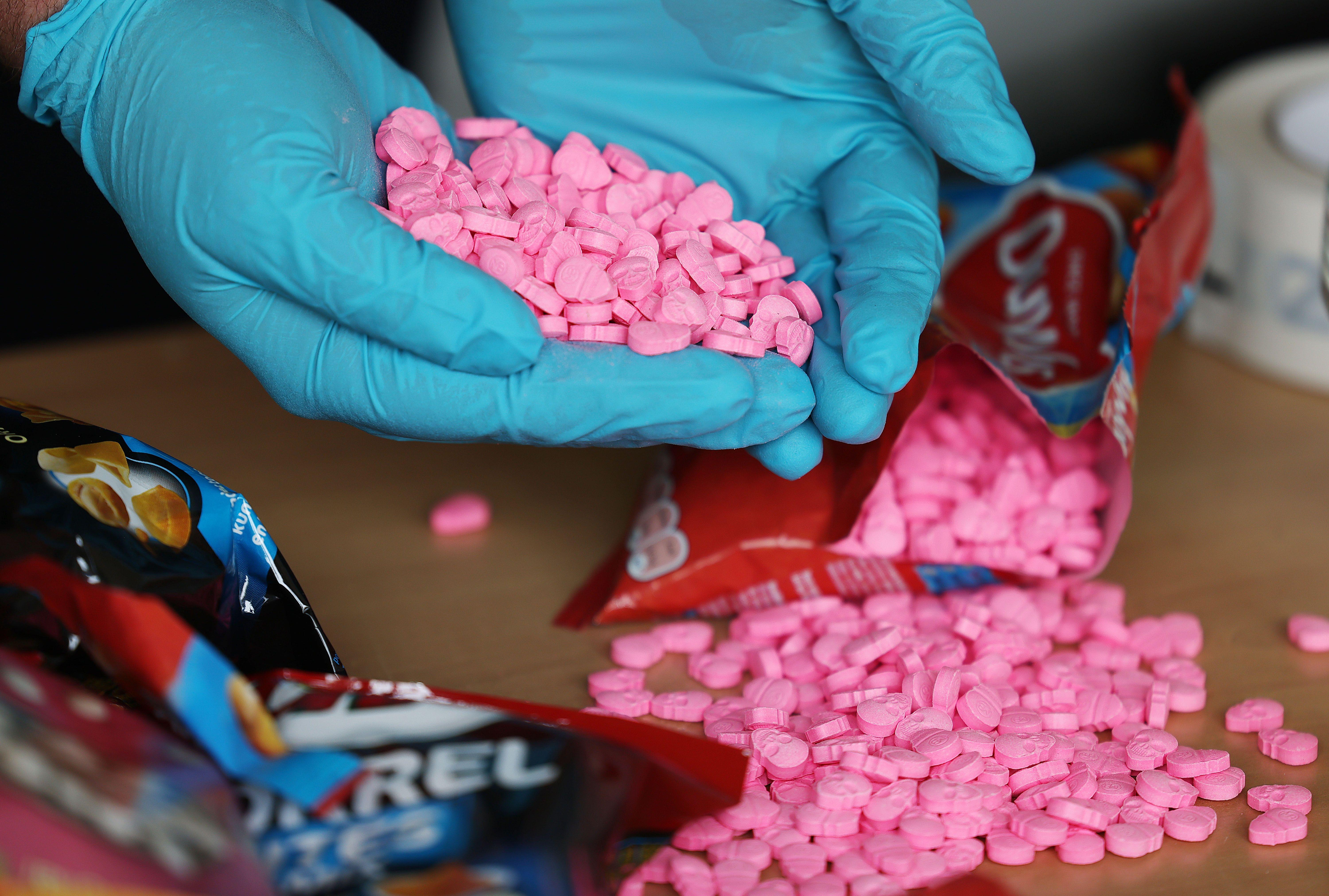 Hände in Gummihandschuhen halten sichergestellte Ecstasy-Tabletten in Totenkopf-Form