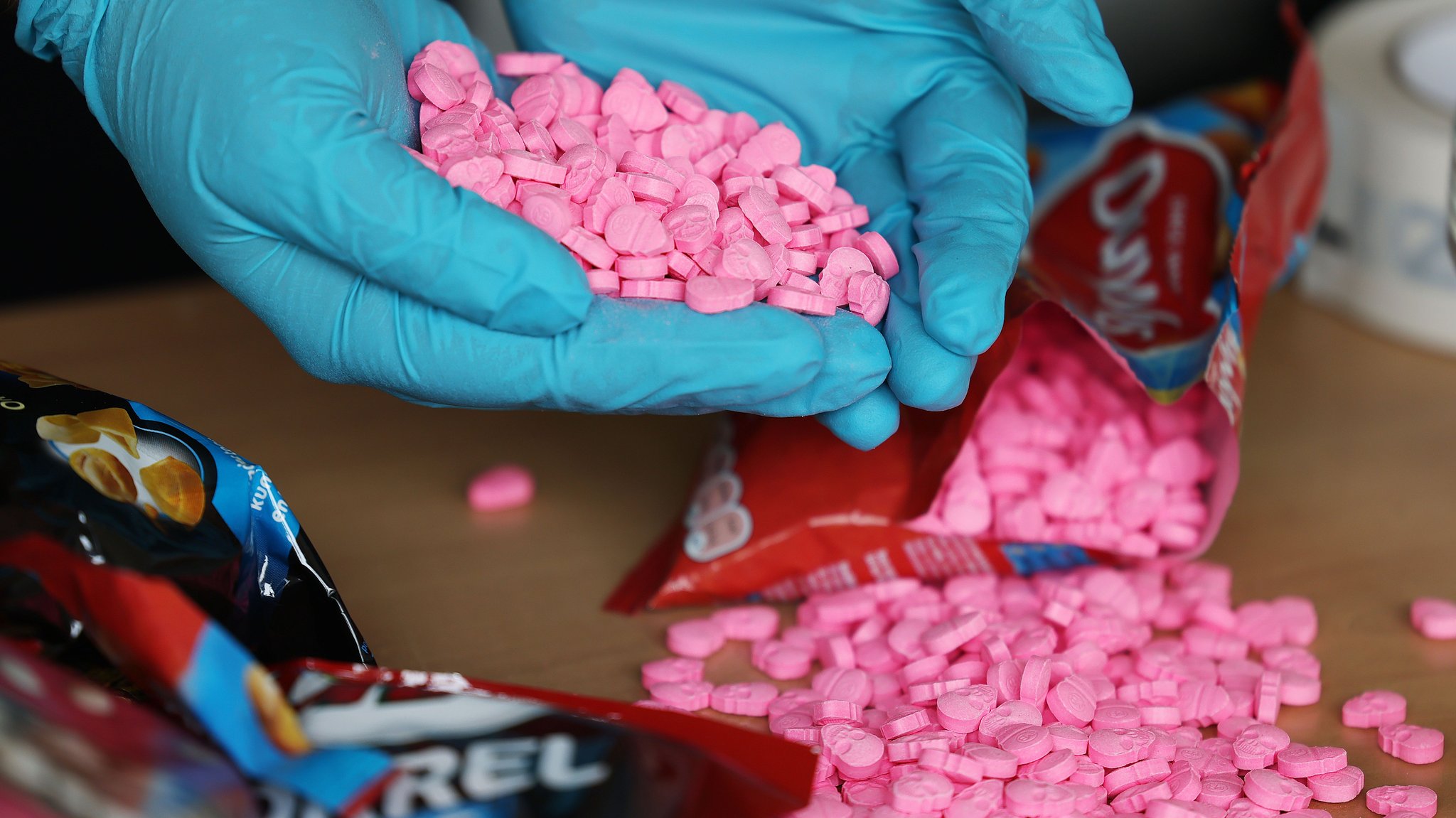 Hände in Gummihandschuhen halten sichergestellte Ecstasy-Tabletten in Totenkopf-Form
