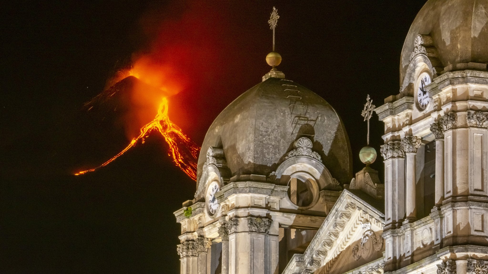 Lava strömt den Ätna herab. Im Vordergrund die Kirche Santa Maria in der Gemeinde Zafferana Etnea.