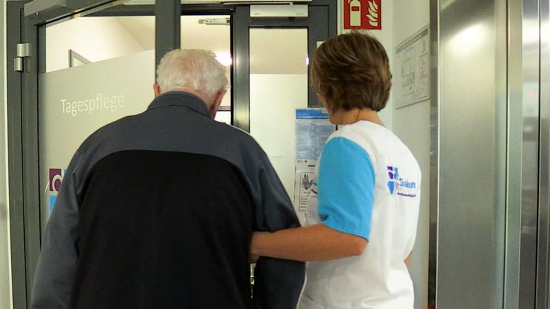 Frau mit Rentner am Eingang einer Tagespflege.