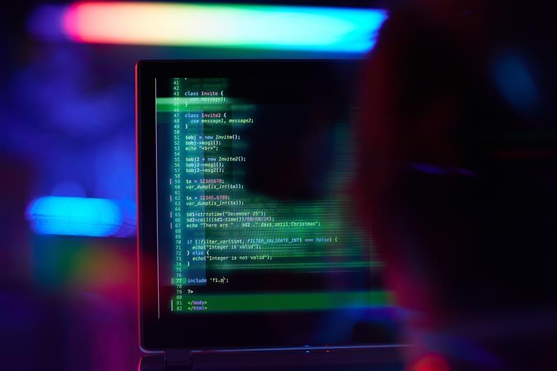 Eine Person sitzt vor einem Bildschirm, auf dem Programmier-Codes zu sehen sind.