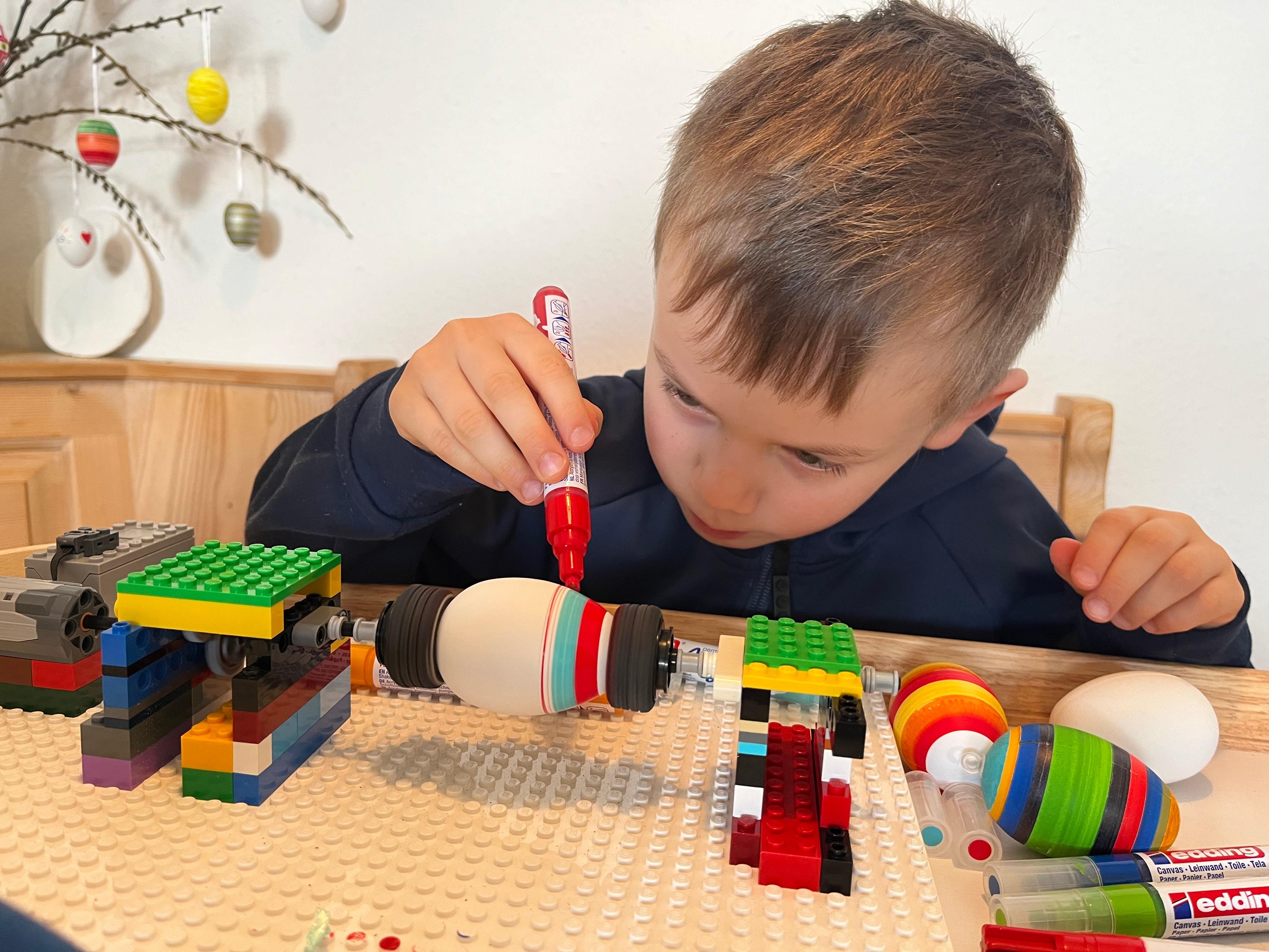Mit Hilfe einer selbst gebauten Lego-Maschine und Acrylstiften fertigt der Fünfjährige bunte Ostereier. 